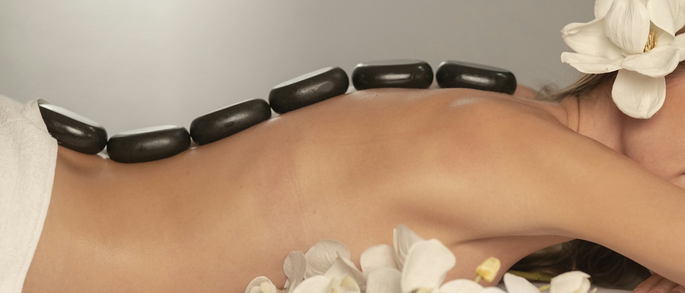 Hot-Stone-Massage mit Orchideen im Wellnessstudio